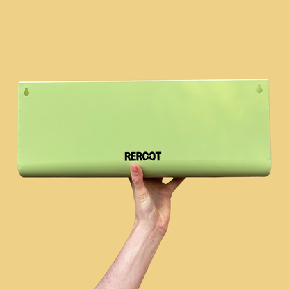 Empty green stainless steel planter held by a person's hand against a yellow background.
